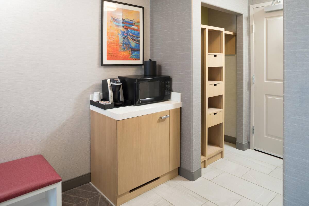Eine kompakte Küchenzeile mit Mikrowelle, Kaffeemaschine und Stauraumschrank.