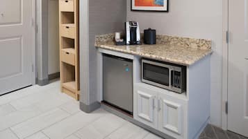 A compact kitchenette with a built-in microwave, a coffee maker, and a small cabinet.