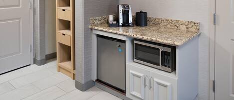 A compact kitchenette with a built-in microwave, a coffee maker, and a small cabinet.