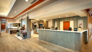 A modern hotel reception area with a central counter, bar area, and a visible minibar. - Hilton Garden Inn Salt Lake City/Sandy (Sandy)