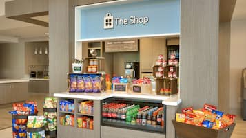 A shop with a blue sign, stocked with snacks, drinks, and other items.