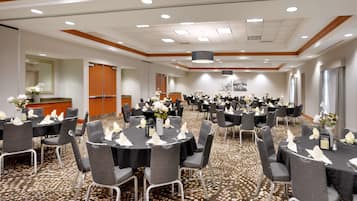 A large conference room with multiple round tables, each set with chairs and centerpieces.