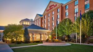 A Hilton Garden Inn with a brick facade, large windows, and a well-maintained lawn with a fountain. - Hilton Garden Inn Salt Lake City/Sandy (Sandy)