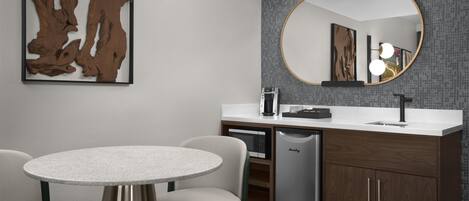 A modern bathroom with a round mirror, a sink, a coffee maker, and a dishwasher.