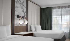 A hotel room with two beds, a marble wall, a wooden headboard, a nightstand, and a window with curtains. - Embassy Suites by Hilton Jackson North Ridgeland (Ridgeland)