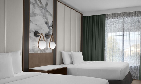 Quarto de hotel com duas camas, parede de mármore, cabeceira de madeira, mesa de cabeceira e janela com cortinas.