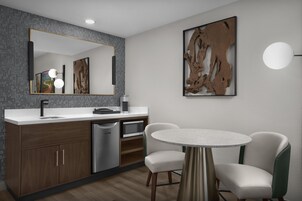 Una cocina moderna con lavavajillas integrado, microondas y una mesa de comedor redonda con dos sillas.