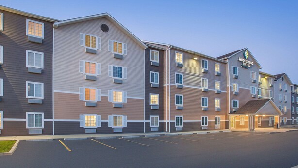 A multi-story hotel with a modern design, featuring a central entrance and multiple balconies. - WoodSpring Suites Sioux Falls (Sioux Falls)