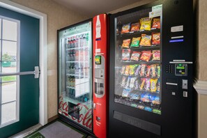 A vending machine with a Coca-Cola logo and a snack vending machine next to a door.