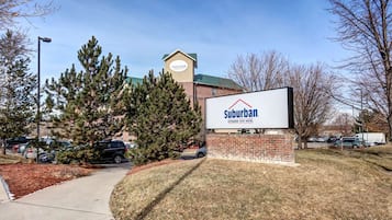 A Suburban Extended Stay Hotel sign with a brick building and a green roof in the background.