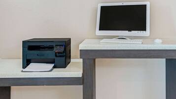 A printer and monitor on a desk with a keyboard and mouse.