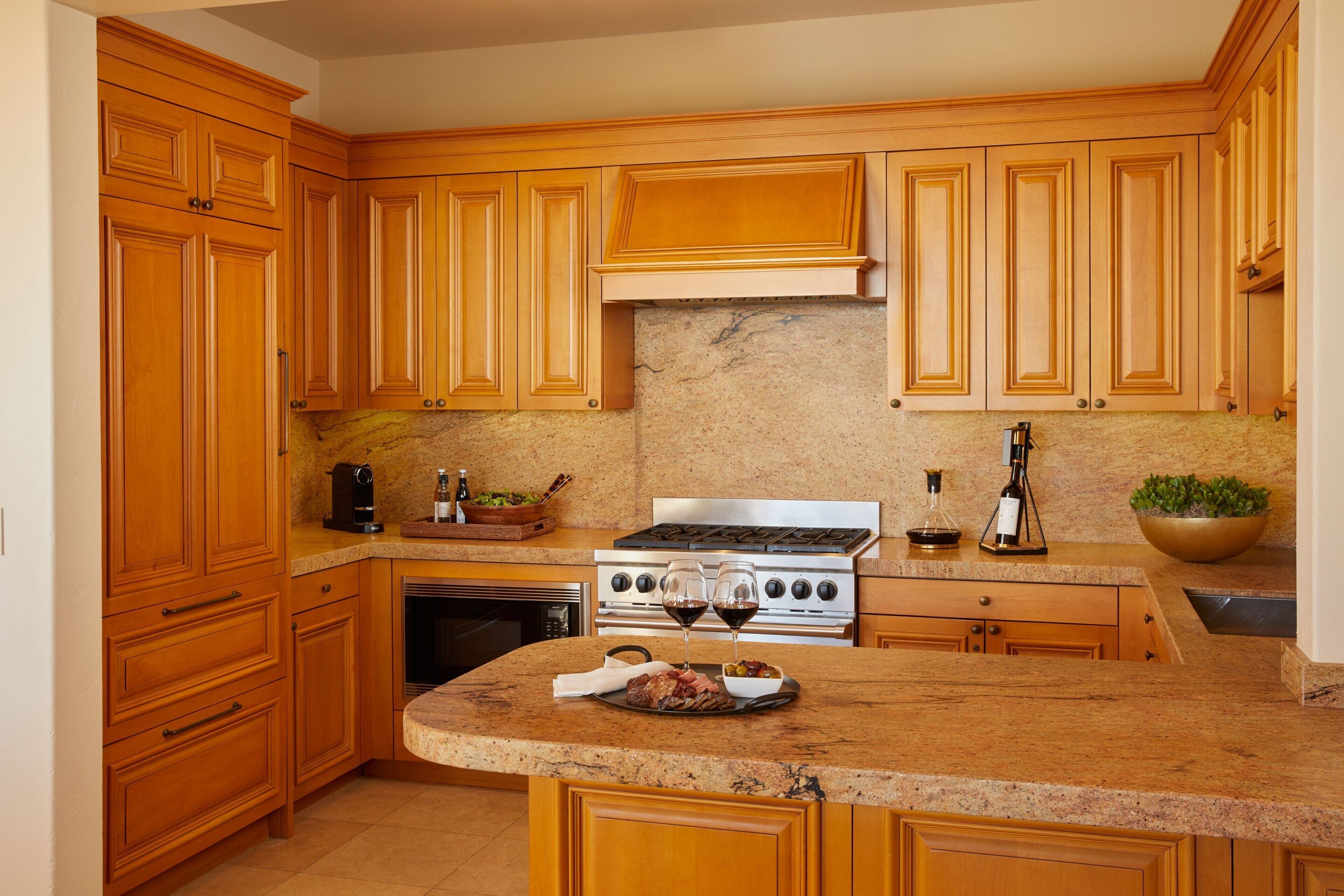 A kitchen with wooden cabinets, a granite countertop, a stove, and a sink.