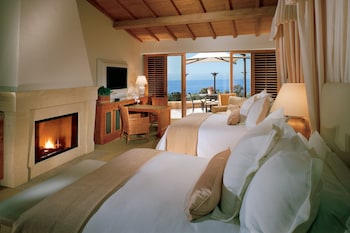 Enjoy ocean views from the comfort of this cozy room, featuring a fireplace, two beds, and a seating area with a table and chairs. at The Resort at Pelican Hill