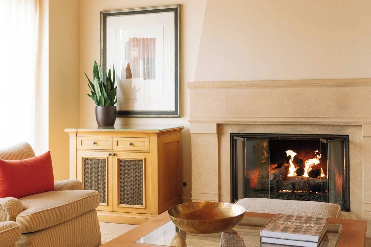 Ein Wohnzimmer mit Kamin, einer Couch, einem Couchtisch und einem Schrank.
