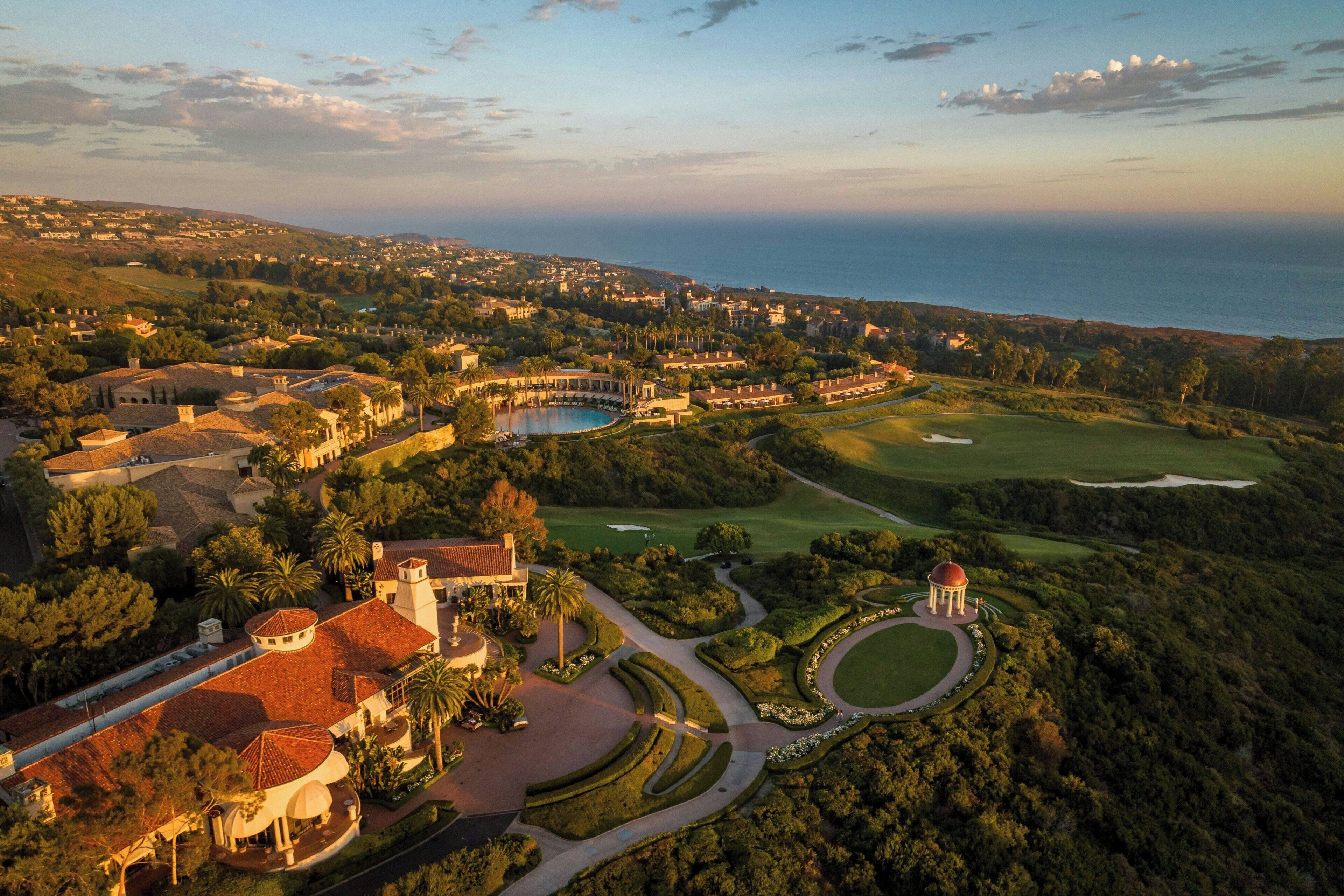 Luchtbeeld van een resort met een golfbaan, een zwembad en een koepelstructuur.