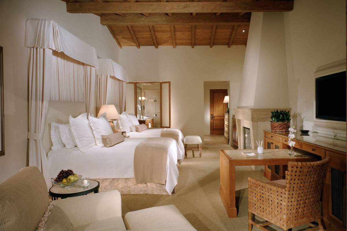 Ein Hotelzimmer mit einem großen Bett, zwei Nachttischen, einem Schreibtisch, einem Sessel und einem Fernseher.