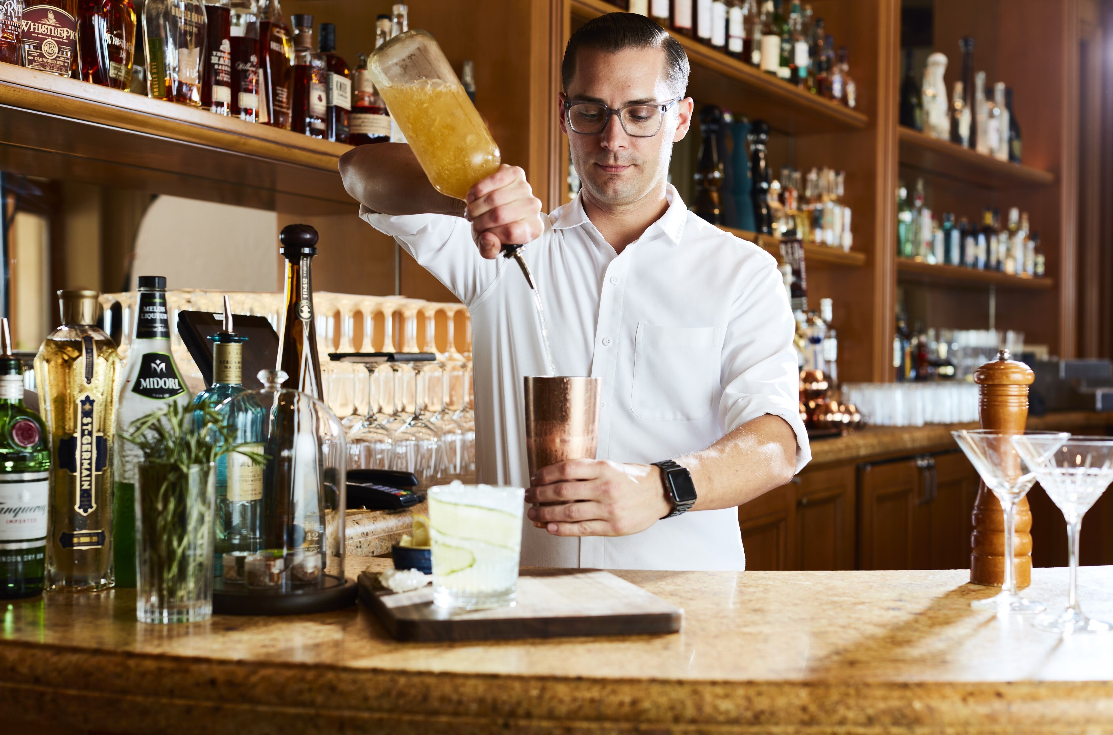 Eine Bar mit einem Barkeeper, der ein Getränk in ein Kupferglas einschenkt.