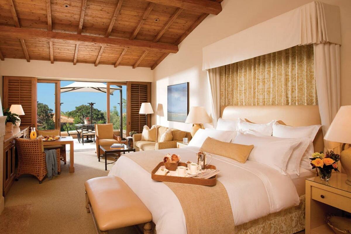 Ein geräumiges Schlafzimmer mit einem großen Bett, einer Essecke und Blick ins Freie.