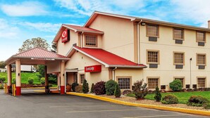 A hotel with a red roof, beige walls, and a covered entrance.