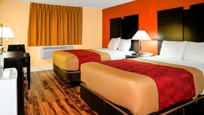 A hotel room with two beds, a desk, a chair, a lamp, and a window with curtains.