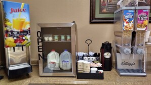 A self-service beverage station with options for orange juice, apple juice, and various dairy products.