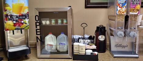 A self-service beverage station with options for orange juice, apple juice, and various dairy products.