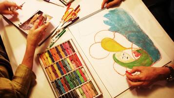Una persona dibujando en un bloc de dibujo con lápices de colores y rotuladores.
