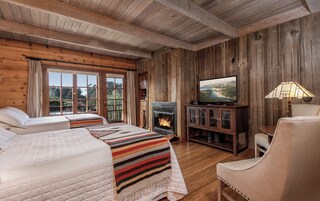 Una habitación acogedora estilo cabaña con dos camas, chimenea, televisor y lámpara.