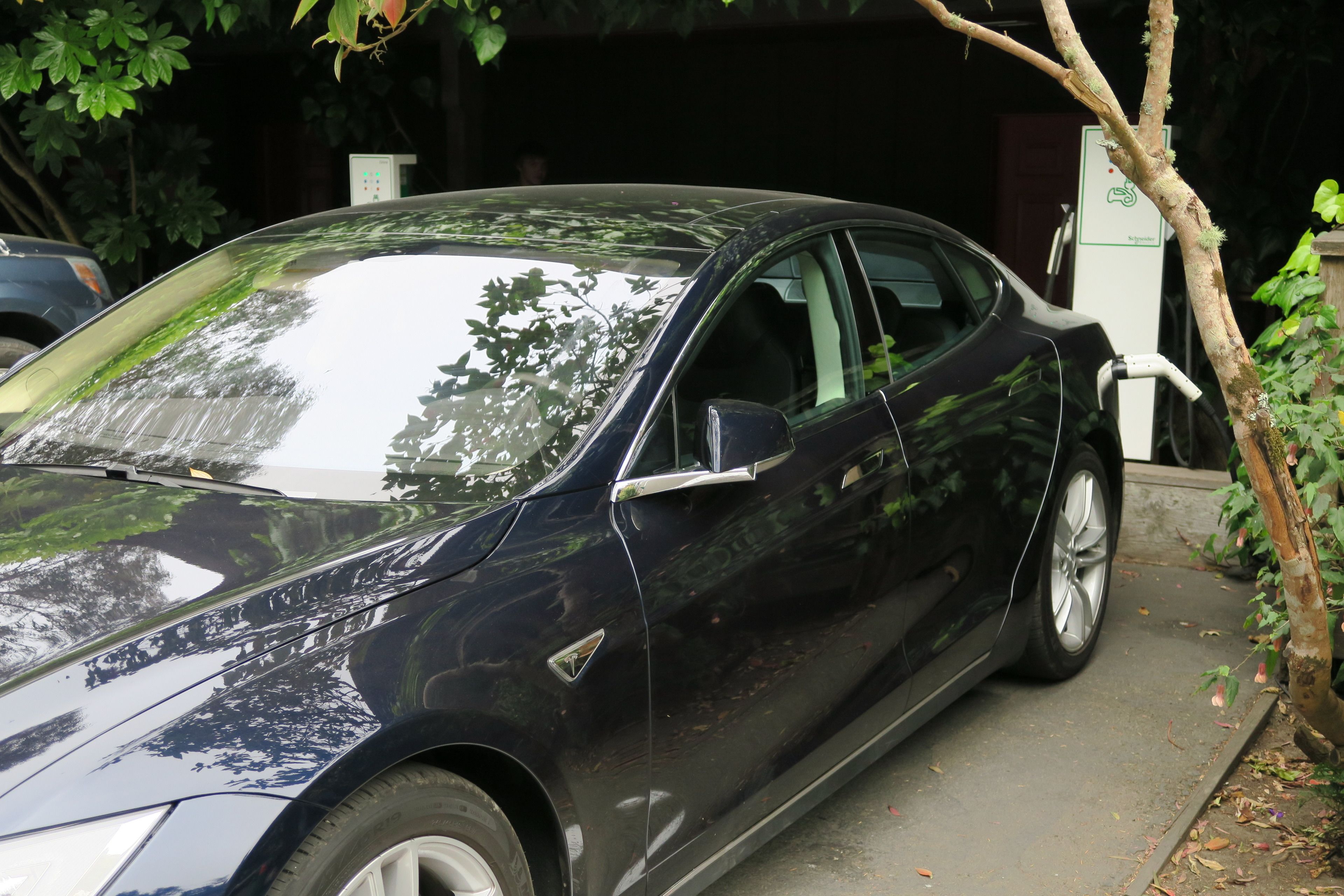 A black car parked in front of a building with a signboard.