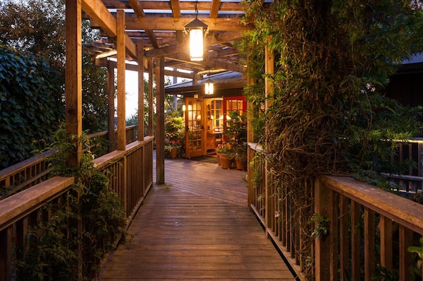 A wooden deck leading to a covered area with a lantern, surrounded by greenery. - The Stanford Inn By The Sea Eco-Resort (Mendocino)