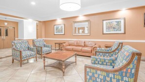 A lobby with a beige sofa, patterned armchairs, a coffee table, and framed artwork on the walls. - Baymont by Wyndham Pearsall (Pearsall)