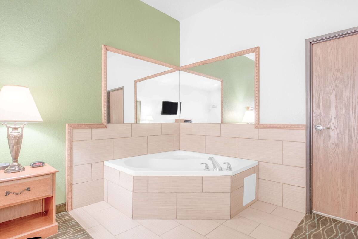 A bathroom with a freestanding bathtub, a vanity with a lamp, and a mirror.