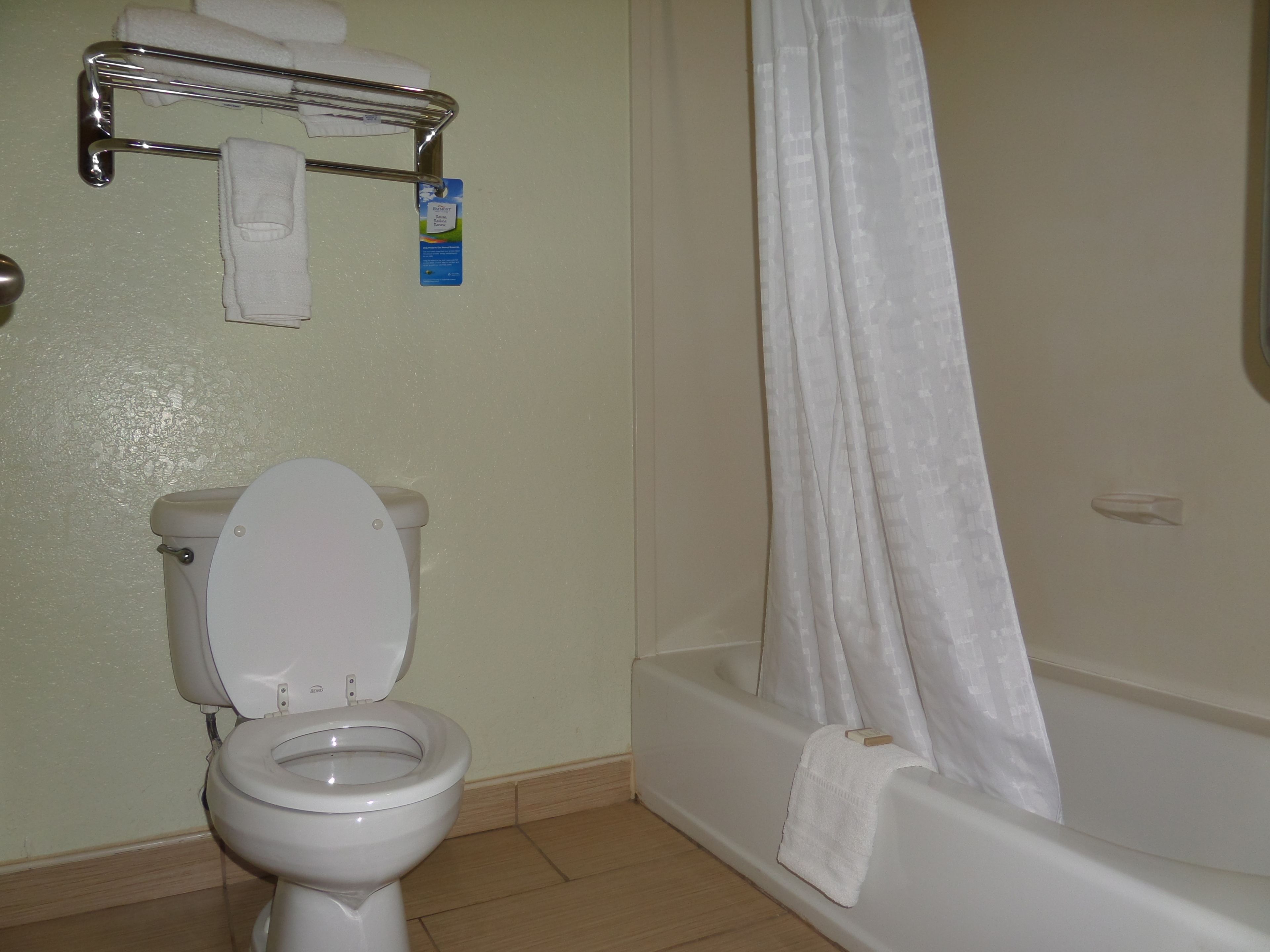 A bathroom with a toilet, a shower curtain, and a towel rack with a towel.