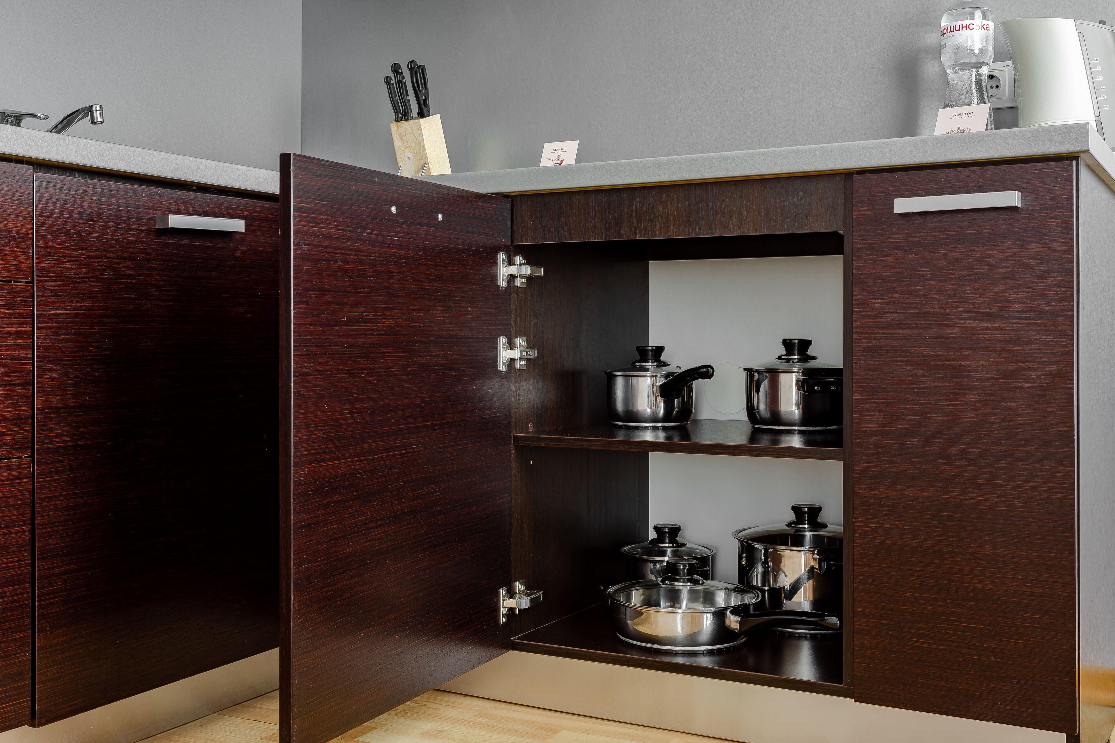 Cocina con alacenas de madera oscura, encimera blanca y varios electrodomésticos.