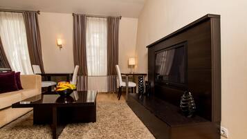 A modern living room with a sofa, coffee table, TV, and a dining area with chairs and a table.