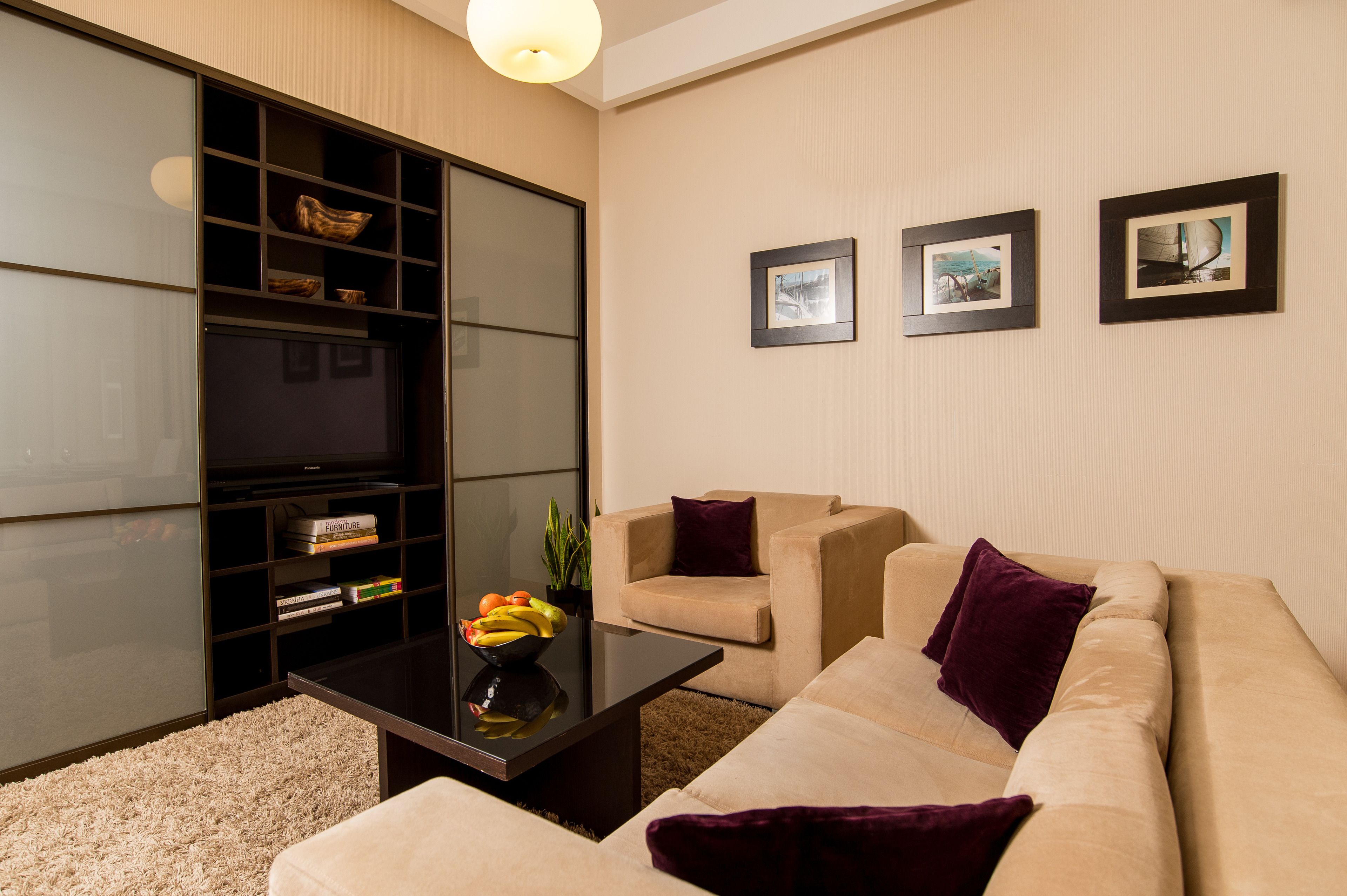 Een moderne woonkamer met een bank, fauteuils, een salontafel en een boekenkast.