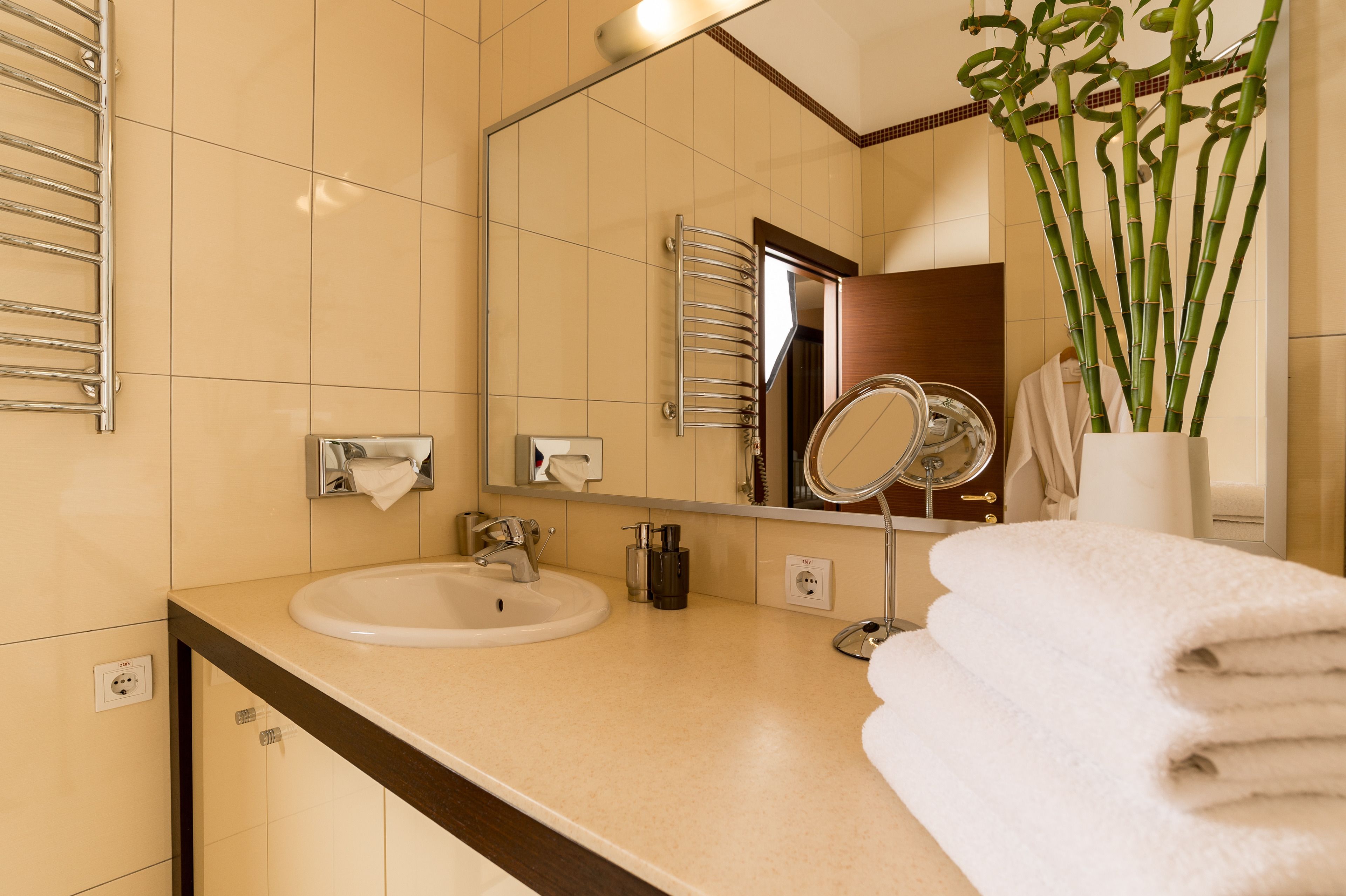 A bathroom with a sink, mirror, towel rack, and a potted plant.