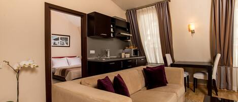 A compact living space with a sofa, a dining table, and a kitchenette.