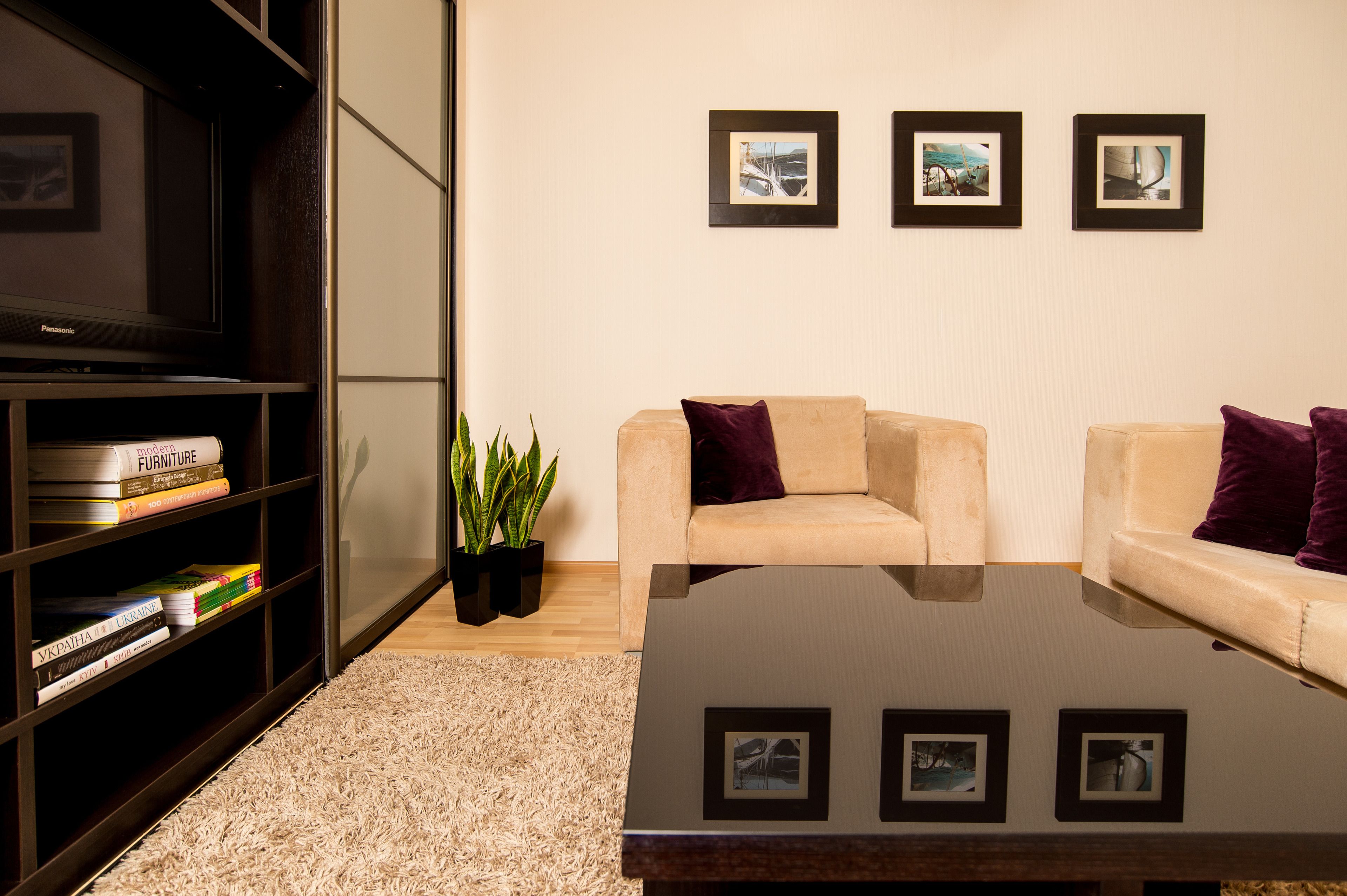 A modern living room with a sofa, a coffee table, a bookshelf, and framed pictures on the wall.