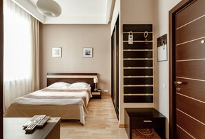 Quarto de hotel com cama, mesa de cabeceira e guarda-roupa embutido.