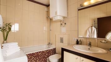 A bathroom with a bathtub, toilet, sink, and a mirror.