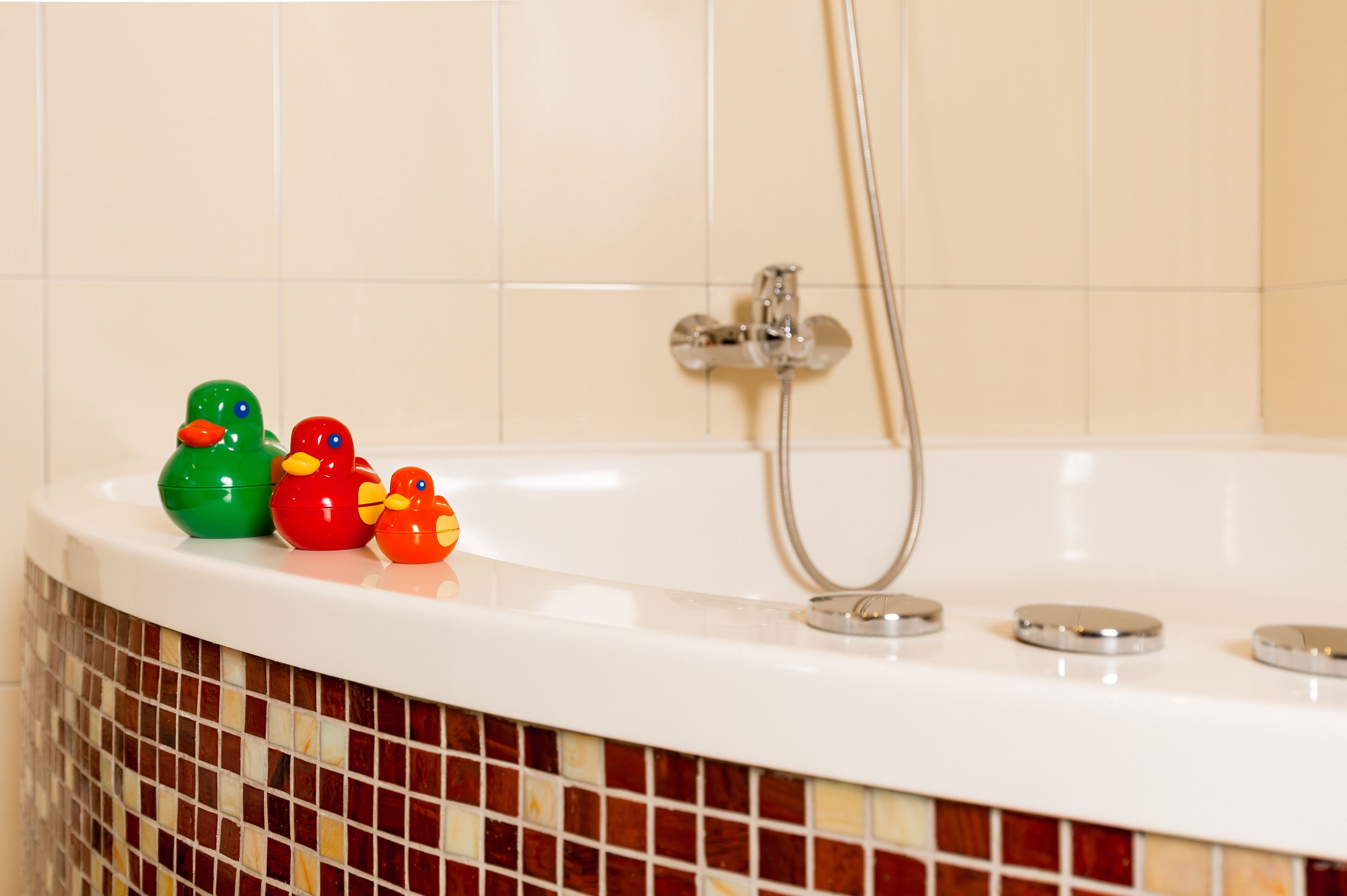 Una bañera con ducha y tres patitos de goma.