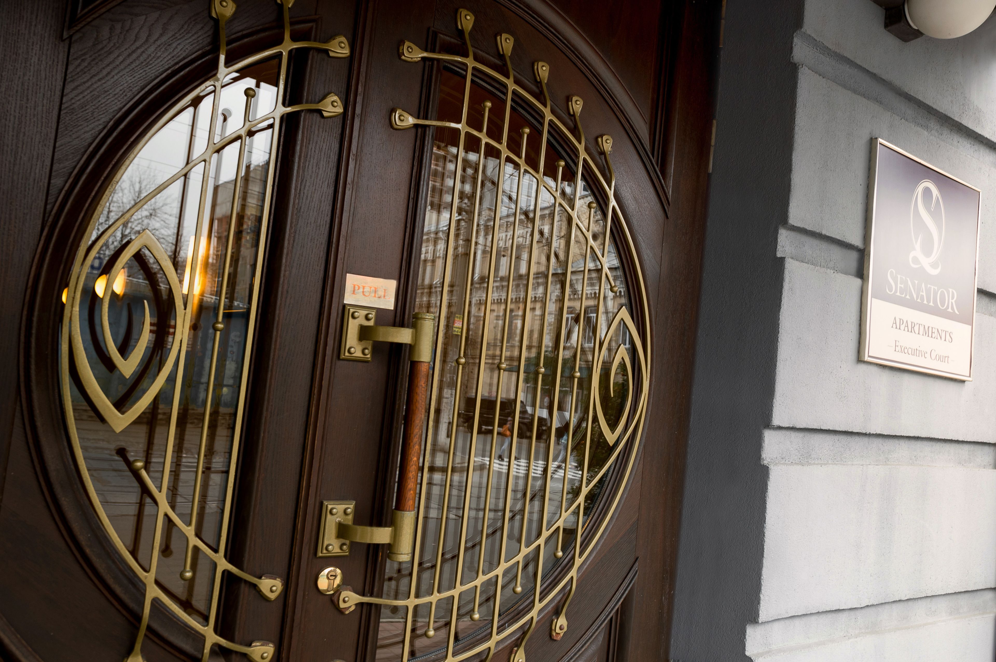 Une porte ornée de motifs métalliques complexes et une plaque indiquant qu’il s’agit de l’immeuble Senator Apartments, situé dans le complexe Executive Court.