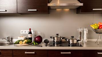 Una cocina moderna con electrodomésticos de acero inoxidable, una botella de vino, verduras frescas y un bol de fruta.