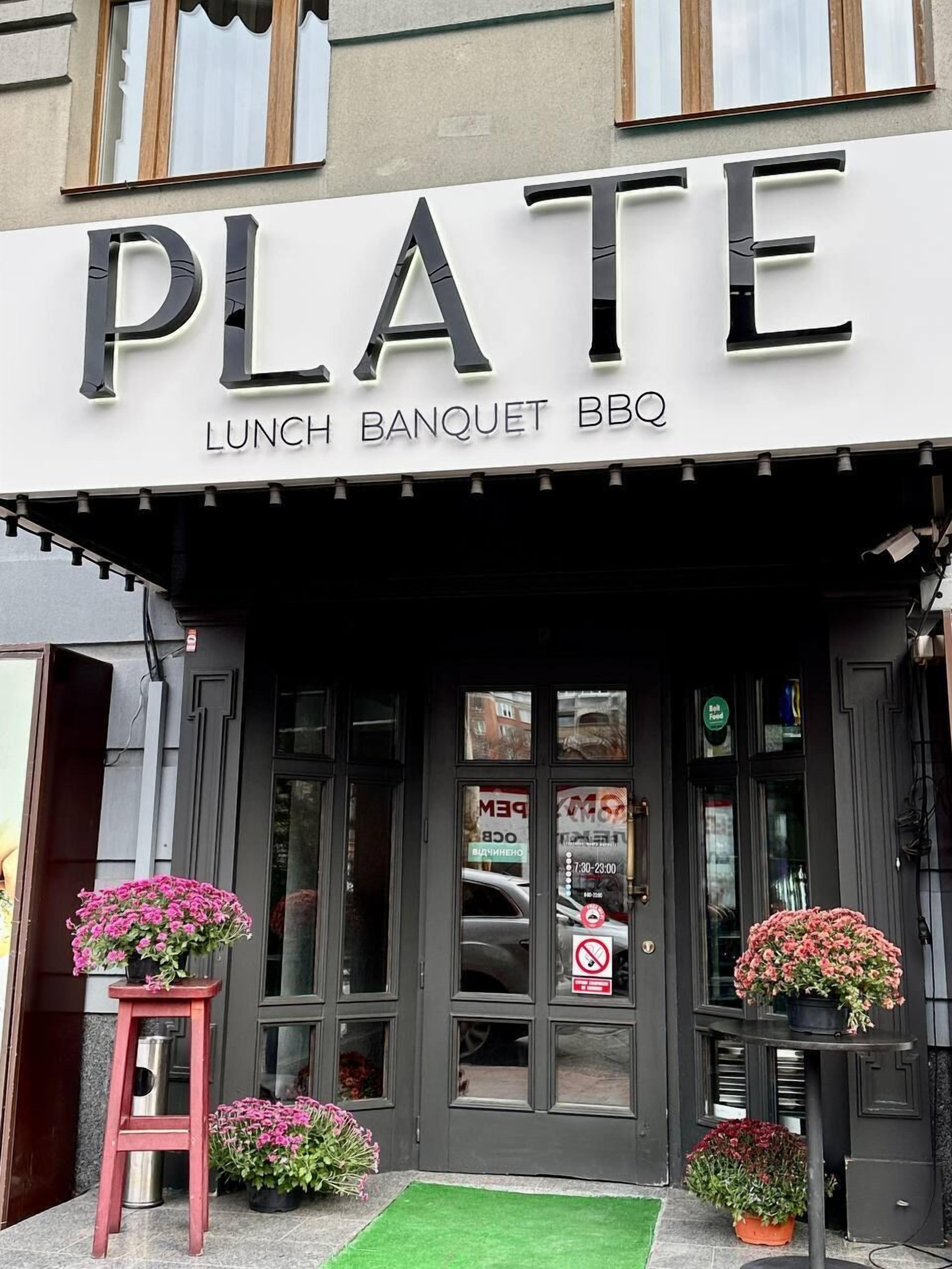 Das Außere eines Restaurants namens "PLATE" mit einem Schild, das Mittagessen, Bankett und Barbecue anbietet.