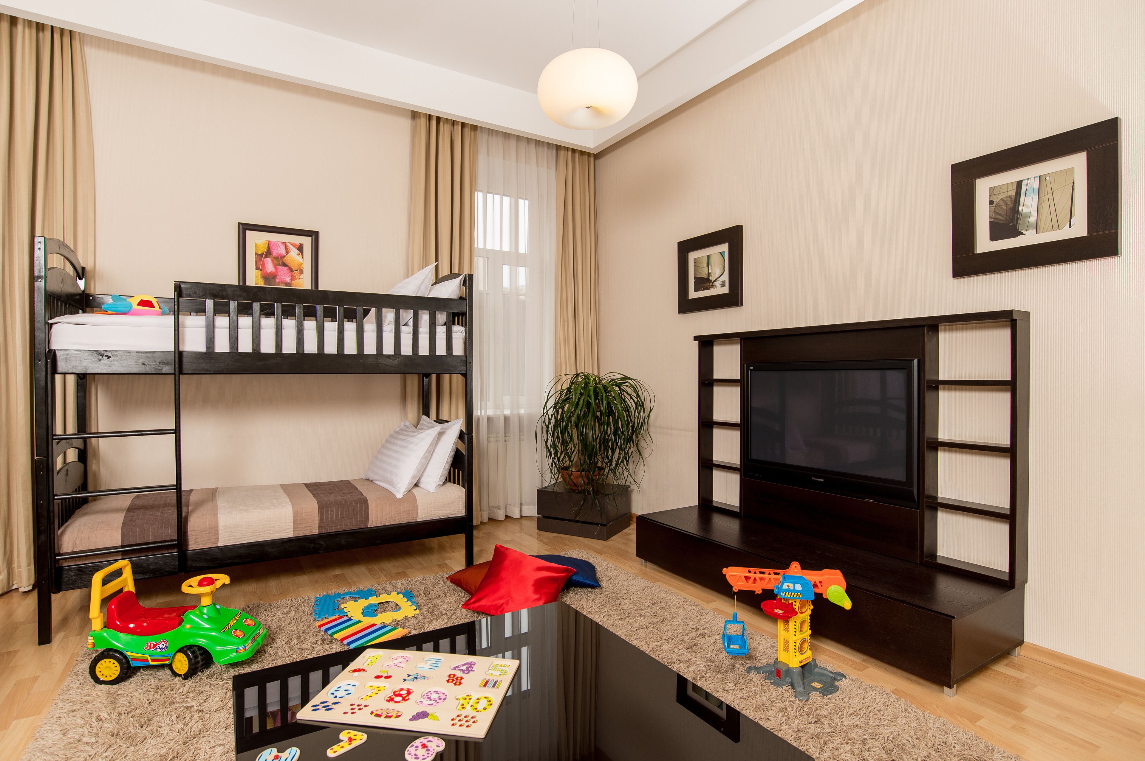 Een kamer met een stapelbed, een televisie, een salontafel en kinderspeelgoed.