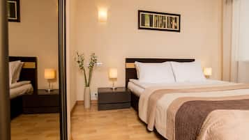 A hotel room with a bed, bedside tables, a mirror, a wall-mounted picture, and a potted plant.
