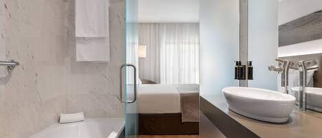 A modern bathroom with a bathtub, a large sink, and a shower area.