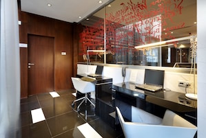 A modern reception desk with a laptop, a telephone, and a glass partition with red text.