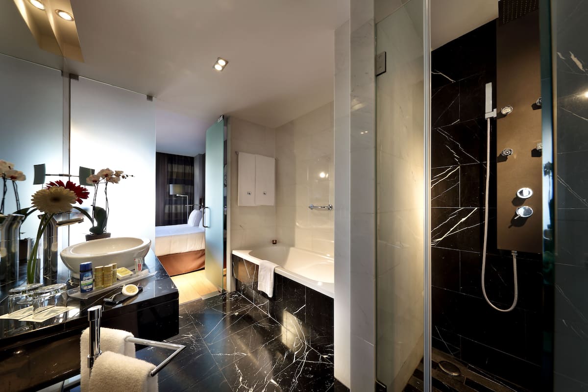A modern bathroom with a large sink, mirror, and a bathtub.
